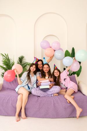 Family celebrating birthday with balloons and gifts on sofa