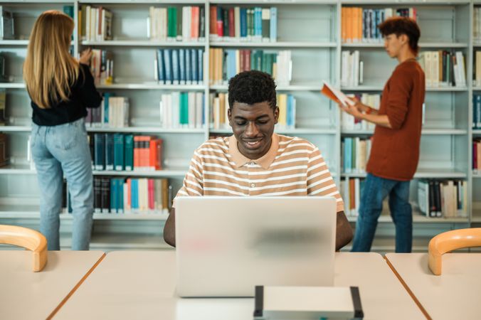 Black student browsing laptop in library