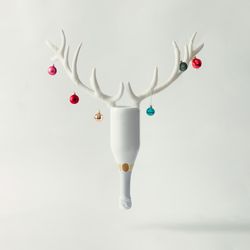 Champagne bottle with reindeer antlers and Christmas baubles