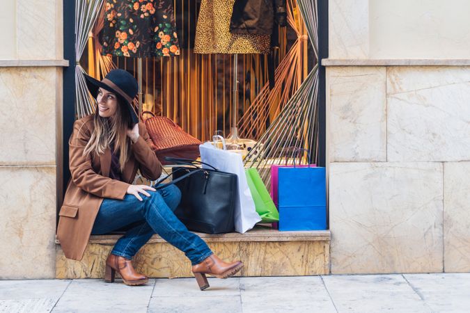 Content young woman in casual outfit resting on street after shopping