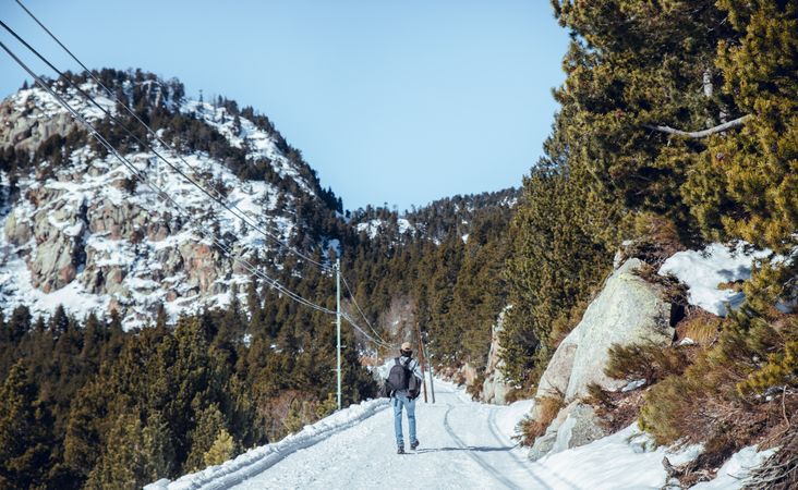 Man walking between hills with trees in winter