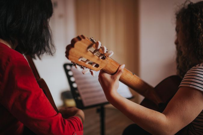 Female students focused on reading guitar sheet music