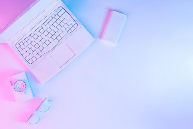 Laptop at desk with camera and smartphone with vibrant bold gradient holographic lights