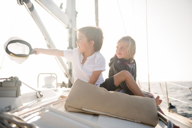 Smiling children sitting on edge of yacht in sea
