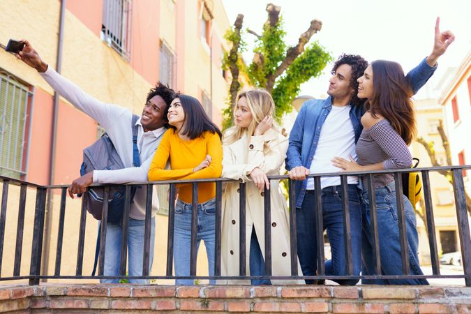 Male and female friends taking selfies together outside