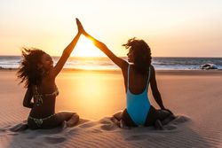 Content Black woman on tropical beach at sunset
