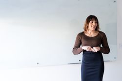 Female in brown knit shirt standing at the front of the room