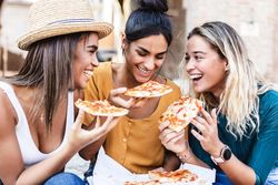 Diverse group of female friends enjoying take away pizza outside