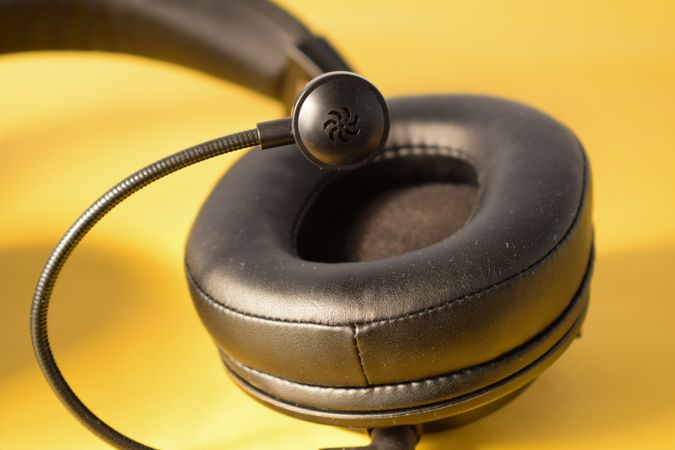 Single headphone ear speaker & mic on yellow table