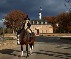 Man riding horseback in military attire from the American Revolutionary era, Williamsburg, Virginia 0gXL75