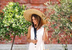 Woman standing between two bushes in front of brick building