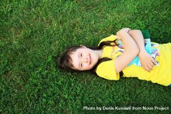 Girl with Down syndrome lying on the grass and smiling 4jD1X0