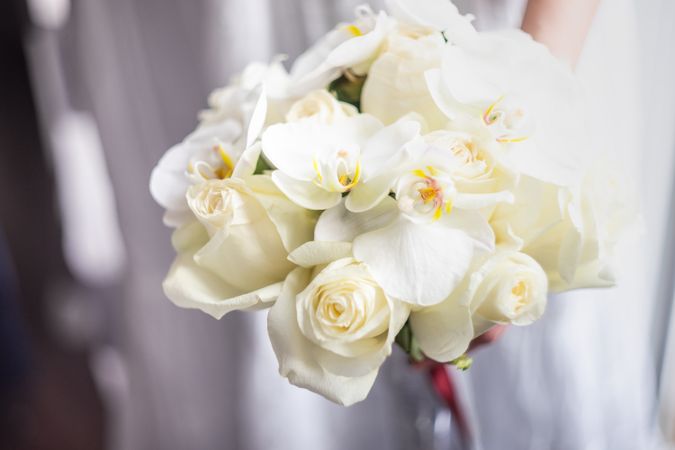 Women holding wedding bouquet with roses and orchids