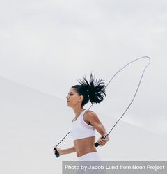 Side view of a fitness woman doing fitness training exercise with rope bGx7V0