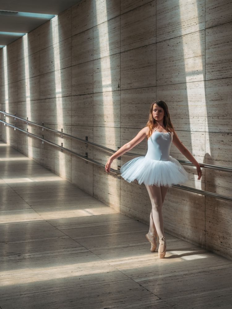 Ballerina doing ballet posing at rail in classroom