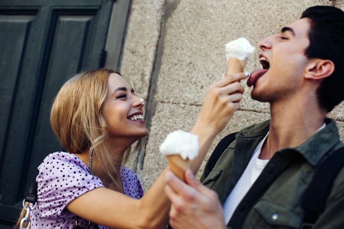Happy couple feeding each other by ice cream