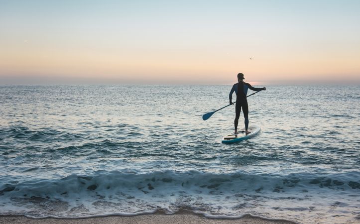 Man practicing paddle surfing with neoprene in a sunrise