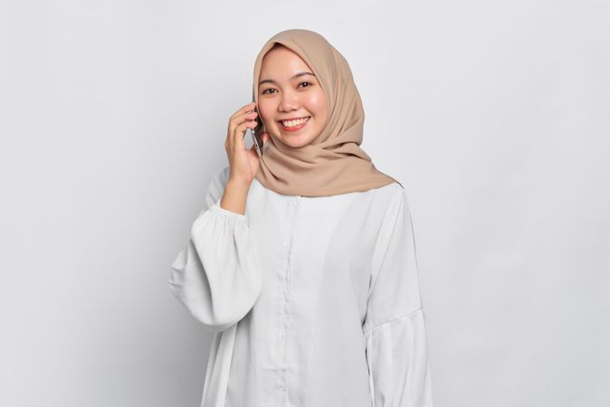 Asian Muslim woman happy while speaking on cell phone