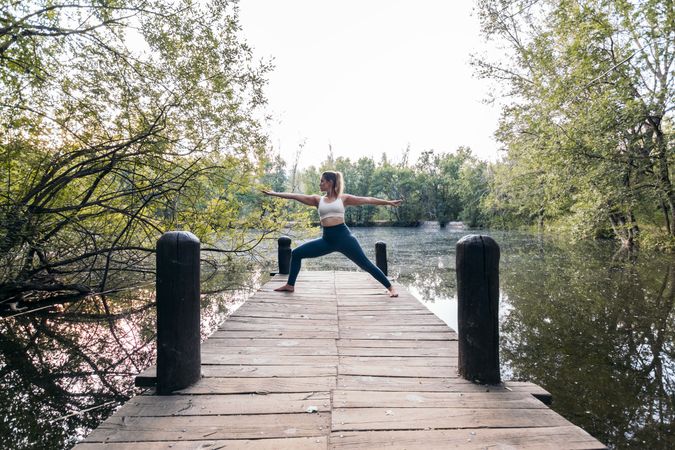 Woman in sportswear doing yoga in nature near a lake