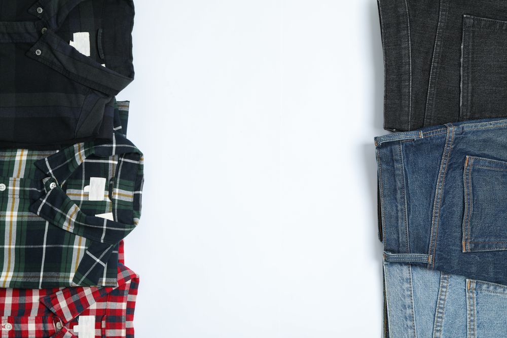 Flat lay with shirts and jeans on plain background