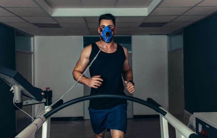 Portrait of runner wearing mask on treadmill in sports science laboratory
