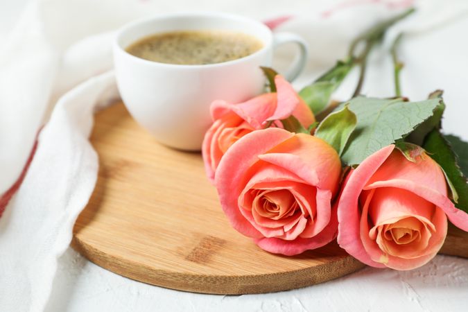 Composition with cup of coffee, roses and kitchen towel, closeup
