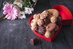 Box full of treats and flowers on wooden table