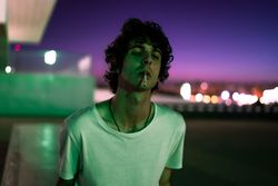 Adult man smoking while looking at camera during sunset