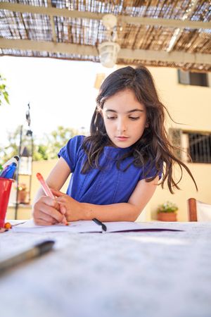 Focused girl drawing picture with felt pens
