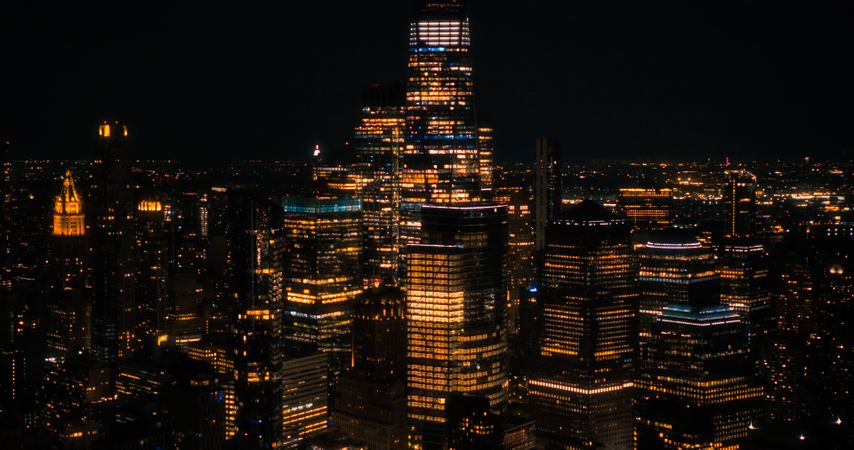 Aerial Helicopter Cinematic Night Scene with a Panoramic View with One World Trade Center Skyscraper and Vibrant Cityscape. Beautiful Office Buildings with Indoors Lights