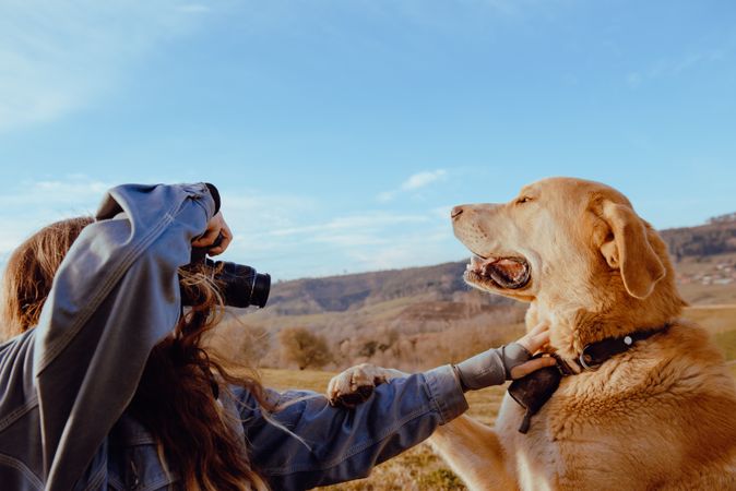 Woman taking photo of dog between field