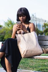 Serious Black woman messaging on smartphone