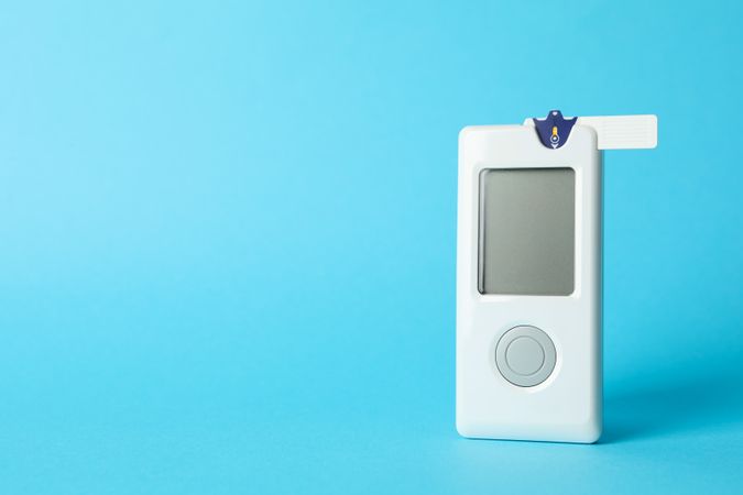 Blood glucose meter on blue background, space for text