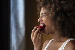 Black woman biting strawberry