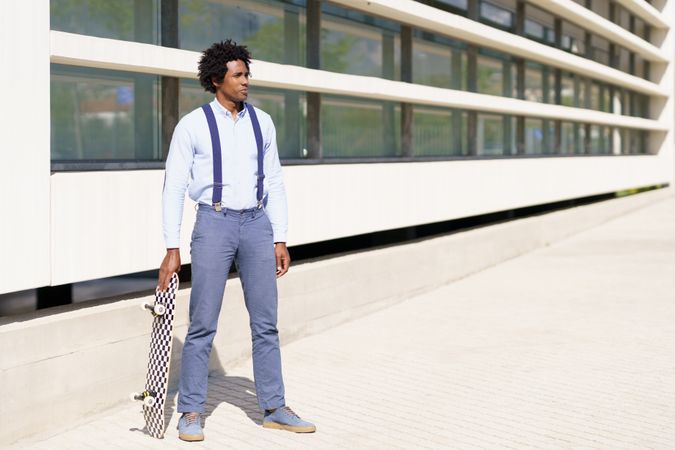Man in business casual with skateboard outside of office