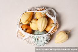Variety of colored pumpkins on light background in mesh bag 0LBly4