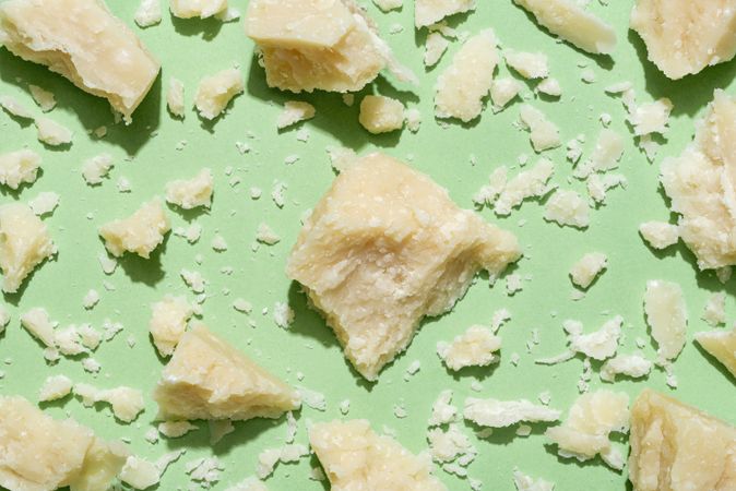 Parmesan pieces and crumbles on a green background