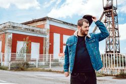 Man taking off cap outside industrial building