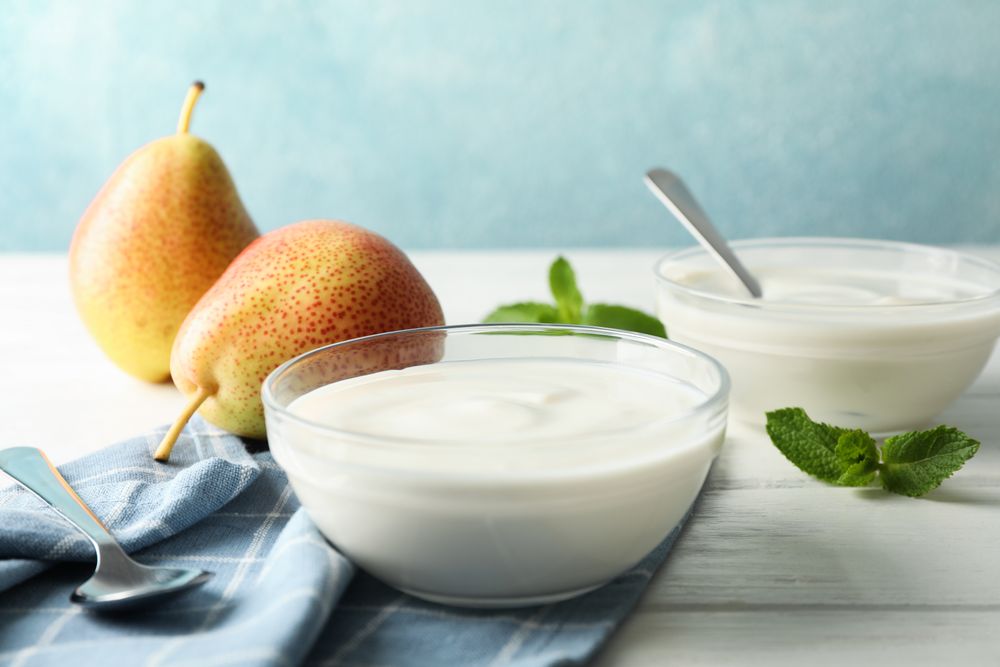 Composition with cream yogurts and fruits on light table, space for text