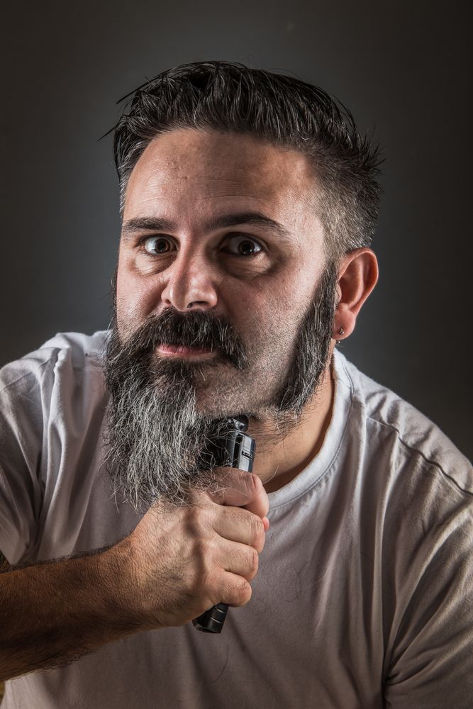 Barber shaving beard and looking at camera