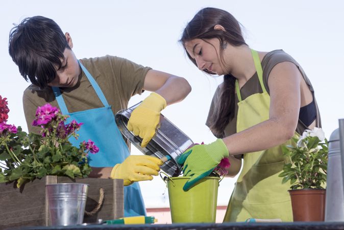 Teenagers wearing a gardener apron while gardening on the terrace