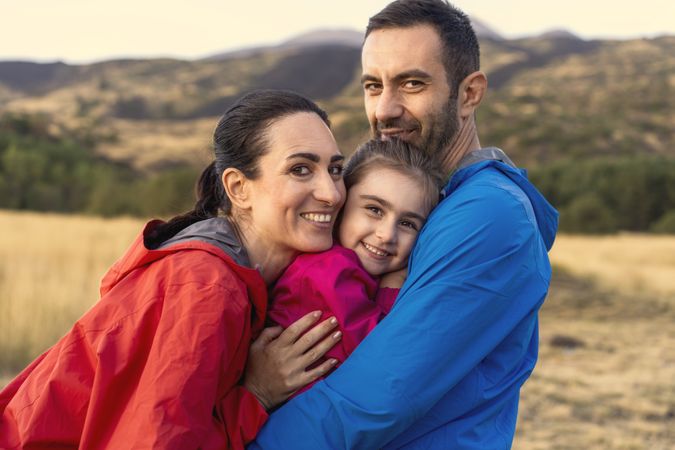 Happy family embracing in nature at sunset, symbolizing love and security.