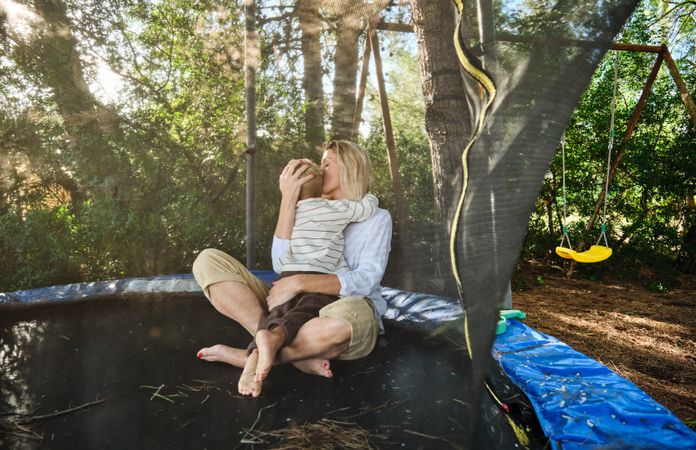 Mother and son sitting on trampoline in playground
