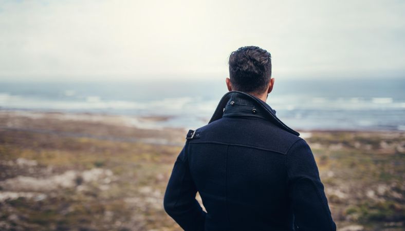 Rear view of man looking at an overcast ocean view