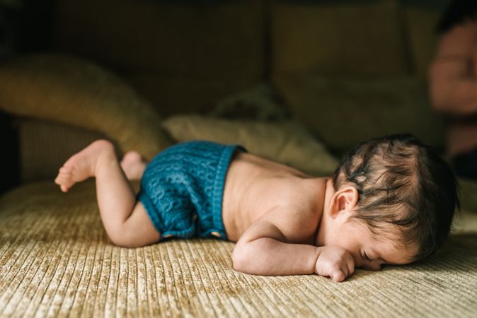 innocent newborn baby in back lying on sofa at home
