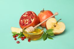 Open pomegranate, apple half, and honey in mint room