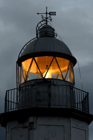 Shining lighthouse against cloudy sky