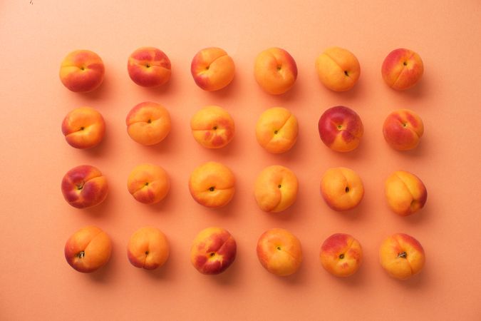 Many apricots organized neatly on an orange background