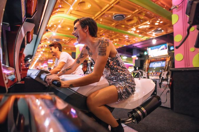 Happy couple having fun playing arcade racing games at a gaming parlour