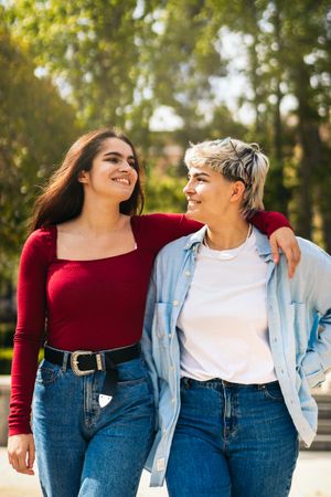 two young women walking and smiling in a park